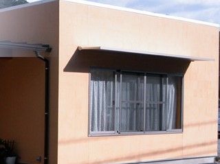 茶色い外壁で、庇のある大きな窓や雨どいのついた建物