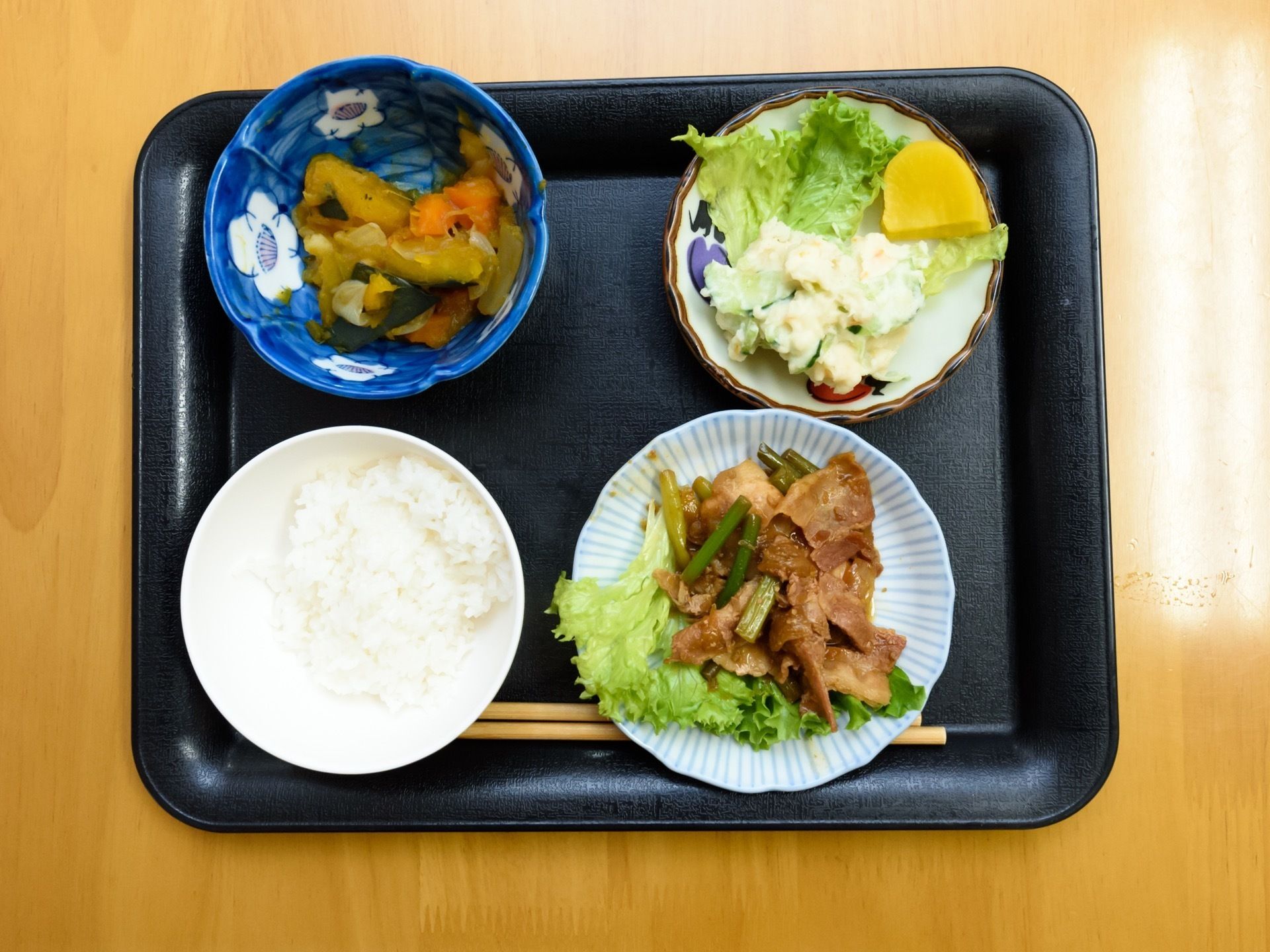 黒いトレイの上には、ご飯と野菜を多く使ったおかずが３品置かれている。彩や栄養バランスを考えて調理されている。