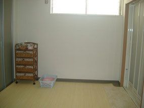 隅に籐の棚が置いてある、壁の上部に窓が付いた脱衣所