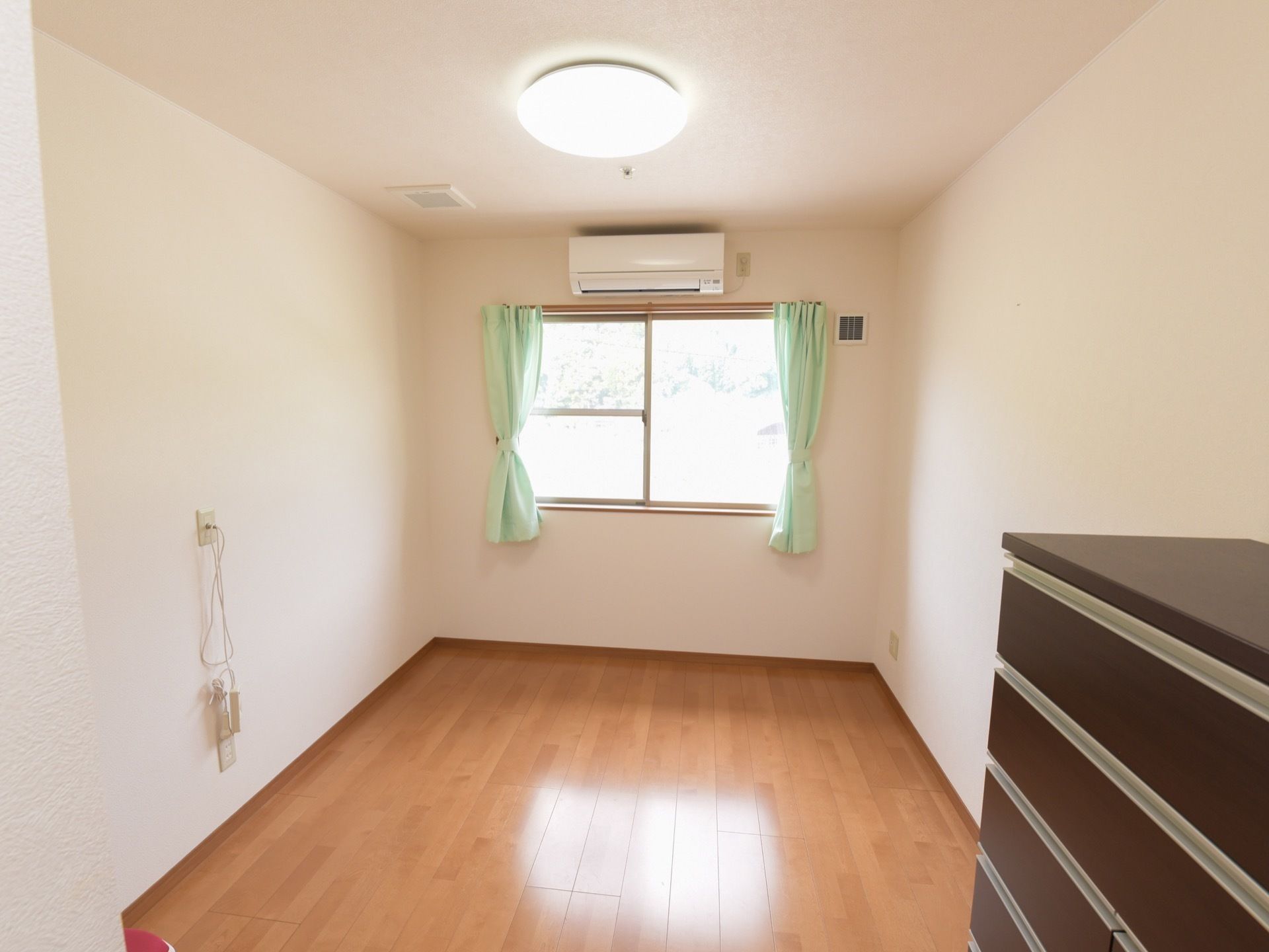 窓からの光と明るい壁紙とが相まって、室内はとても明るく温かみのある雰囲気。窓から見える緑も目に優しい。