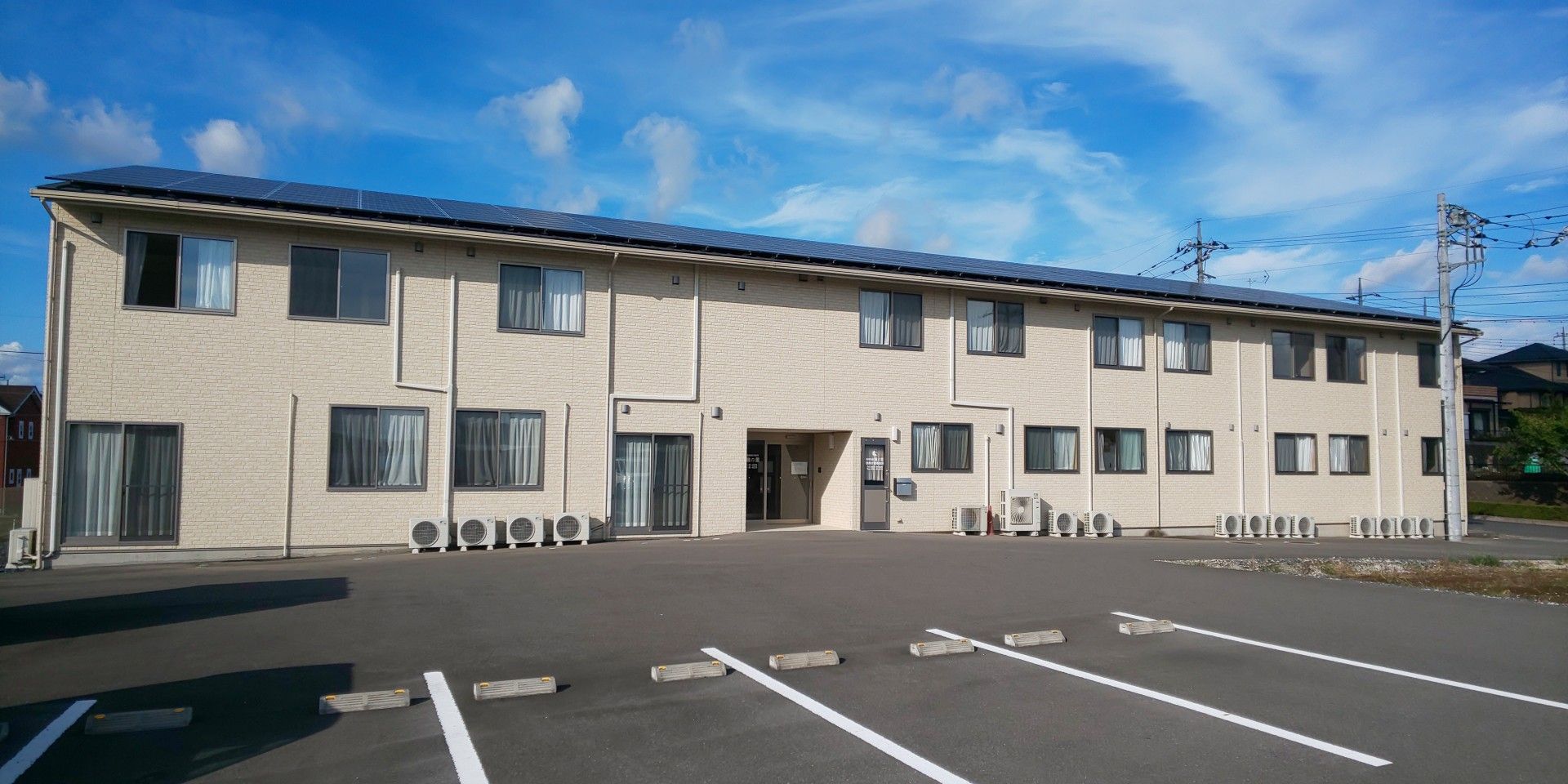 白いタイル張りで、建物の外に室外機の並んだ2階建ての施設