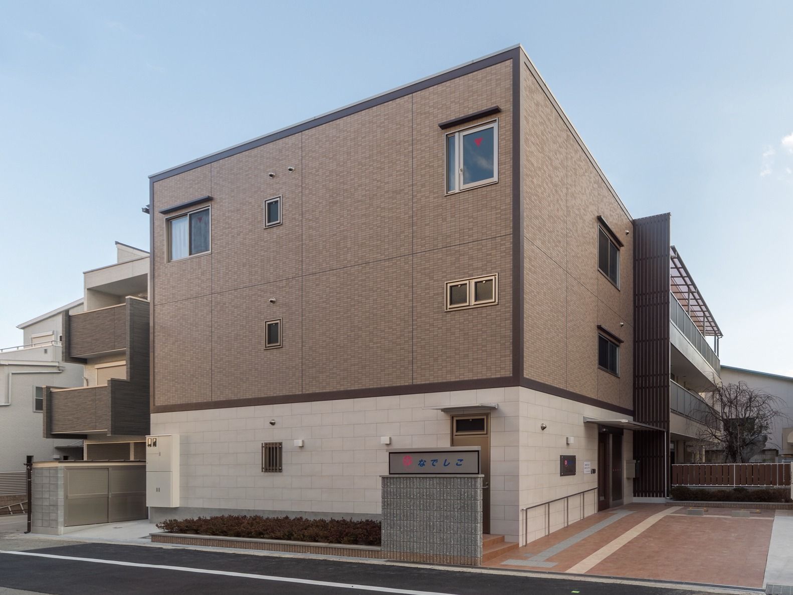 道路から入口までゆるやかなスロープになっている、白と茶色の2色のタイル張りの建物
