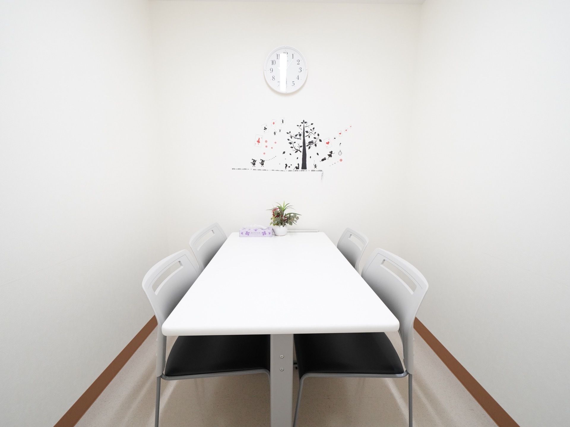 白を基調とした4人掛けの椅子とテーブルが配置された談話室。家族での会話や静かに集まって会話する際に利用することができる。