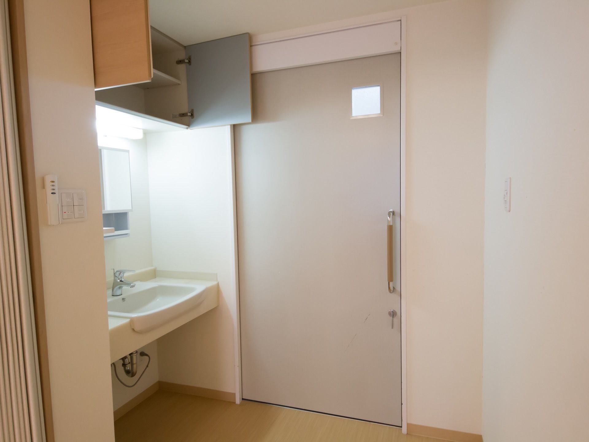 個室トイレの前に、洗面台のスペースが設置されている。大きな鏡があり、上には、観音扉式の棚も付いている。