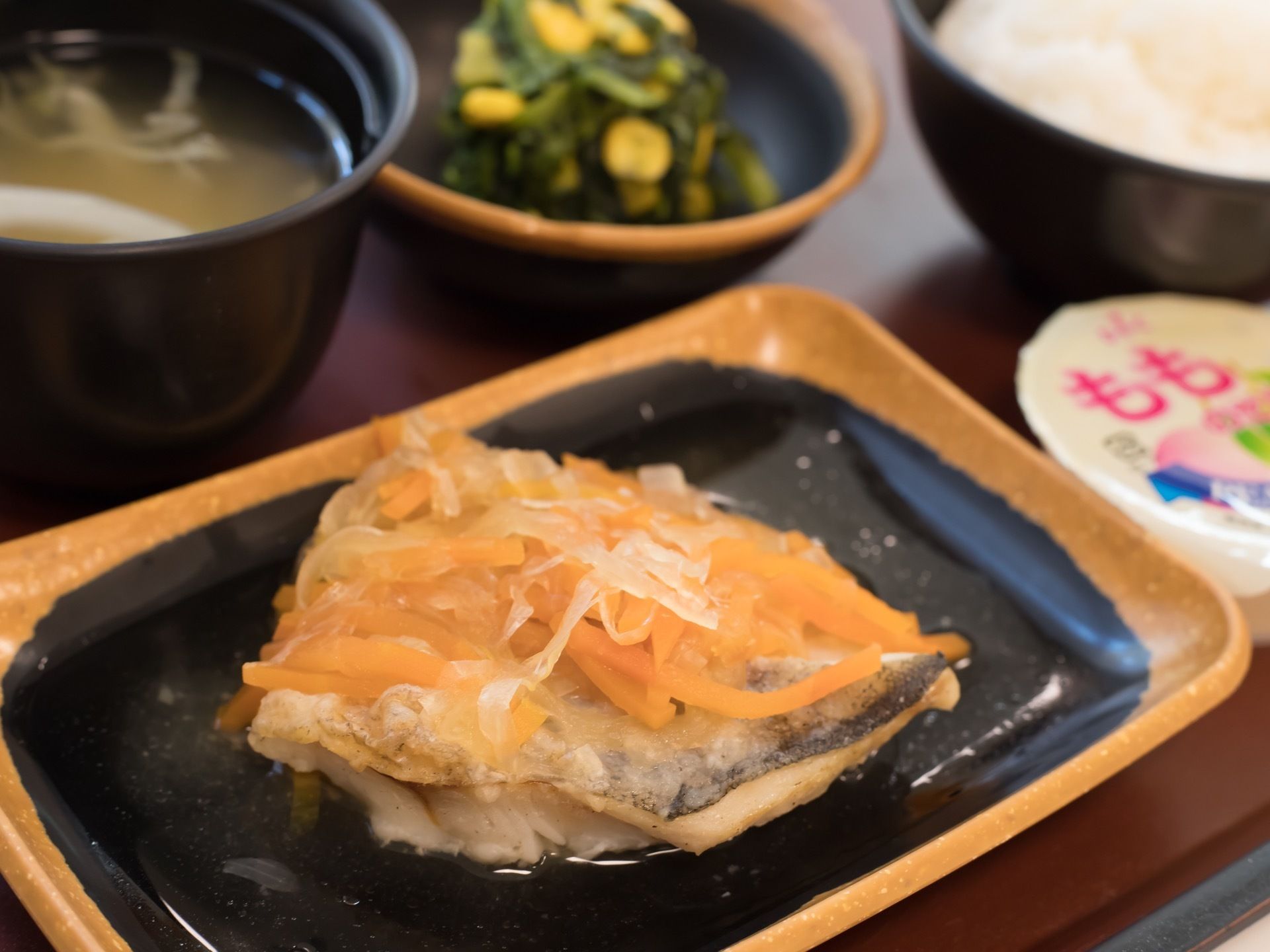 お魚やみそ汁といったバランスの取れた食事が並んでいる。食欲が増すよう、お皿には木の素材を活かしたものが使われている。