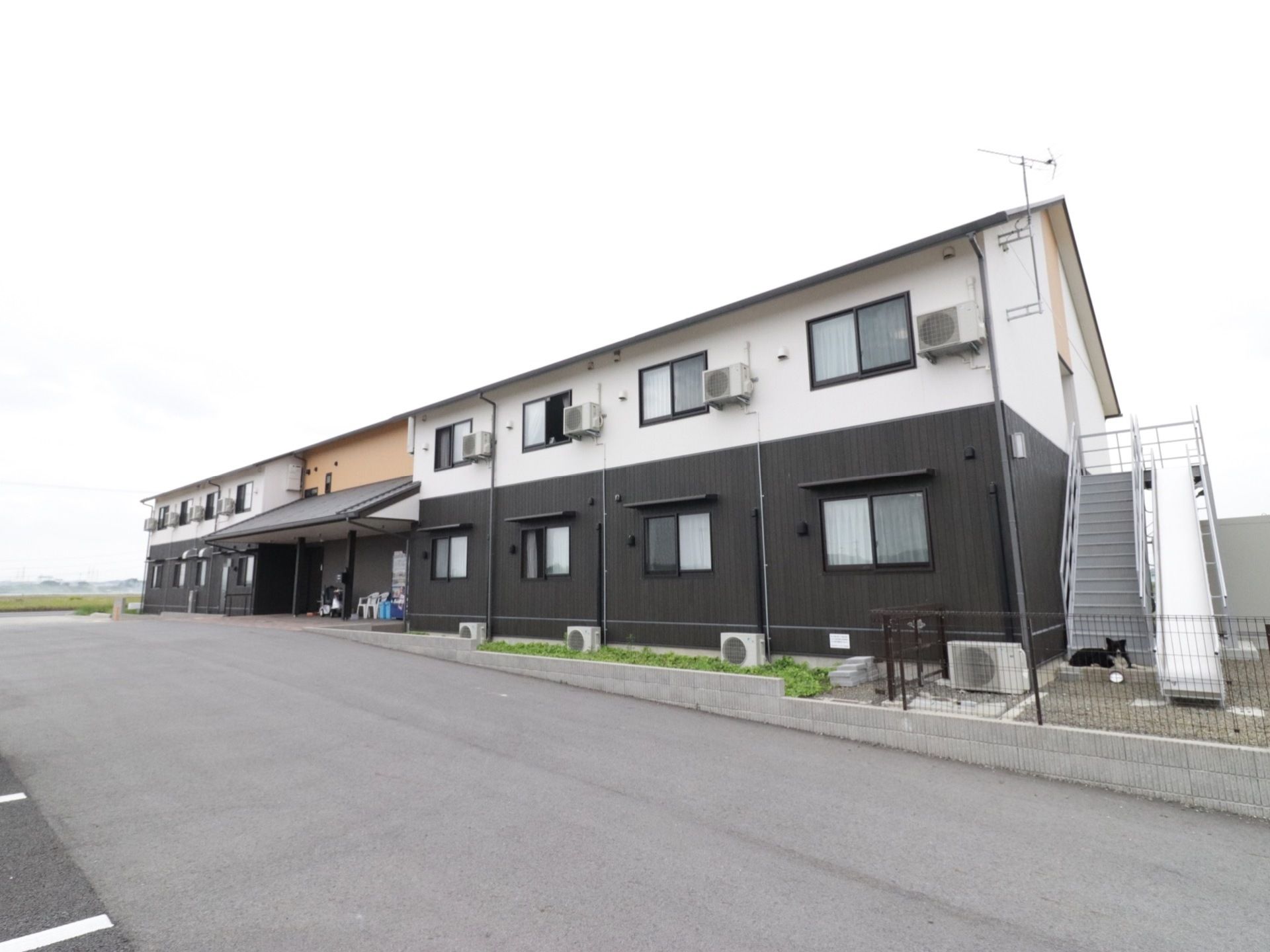 白と黒のツートンカラーと大きな三角屋根が印象的な2階建の建物である。周囲にはのどかな田園風景が広がっている。