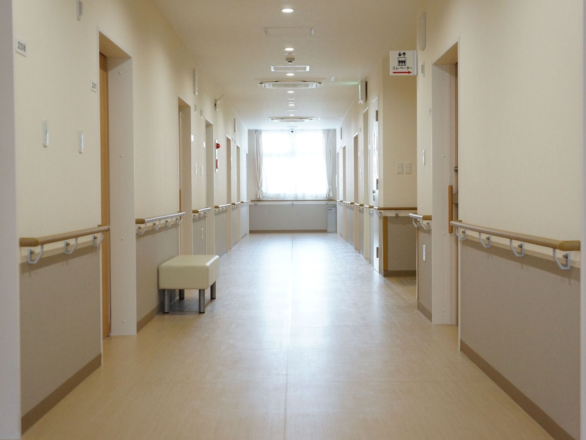 床が明るい木目調で、その他が白色の通路である。両側に居室への扉があり、扉の間には手すりが設置されている。奥には大きな窓が見える。
