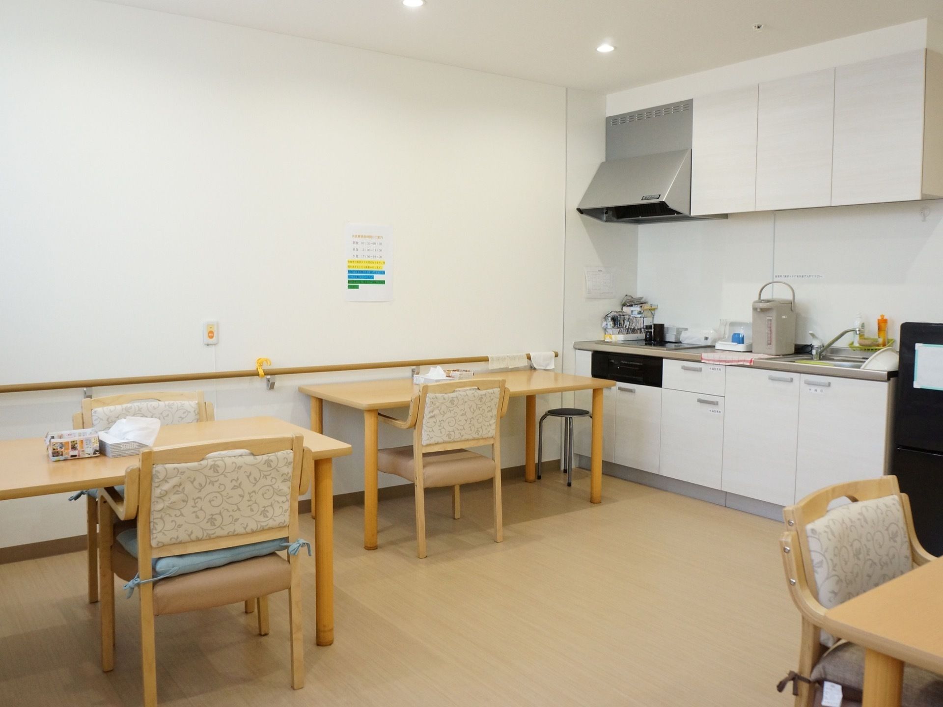 明るい色を基調とした広い空間に、机が複数置かれている。奥にはコンロや流しといった簡単な料理スペースが見える。