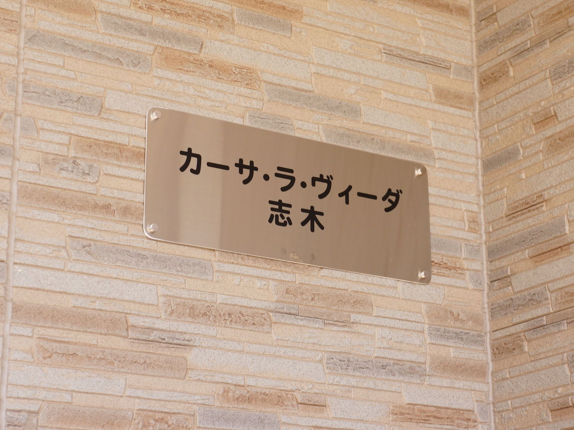 建物入り口の看板には、シルバーの板に黒字で本施設名を記載している。シンプルな造りでわかりやすいようになっている。