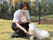 かわいらしい一匹の子犬。ベージュの毛色に黒い鼻で耳が垂れ下がっている。じっとお座りをし、どこかを見つめている。
