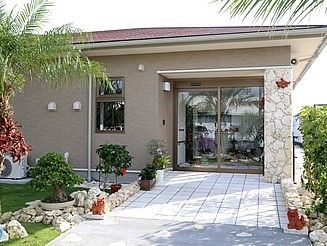 南国を思わせる施設の建物と玄関である。玄関先通路は車椅子をご利用の方も安全に通行可能なバリアフリー構造になっている。