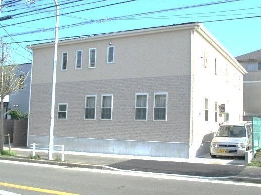 道路に面した２階建ての外観は、箱型のシンプルなデザインである。横に１台の車が停まっている。静かな環境に恵まれた施設である。