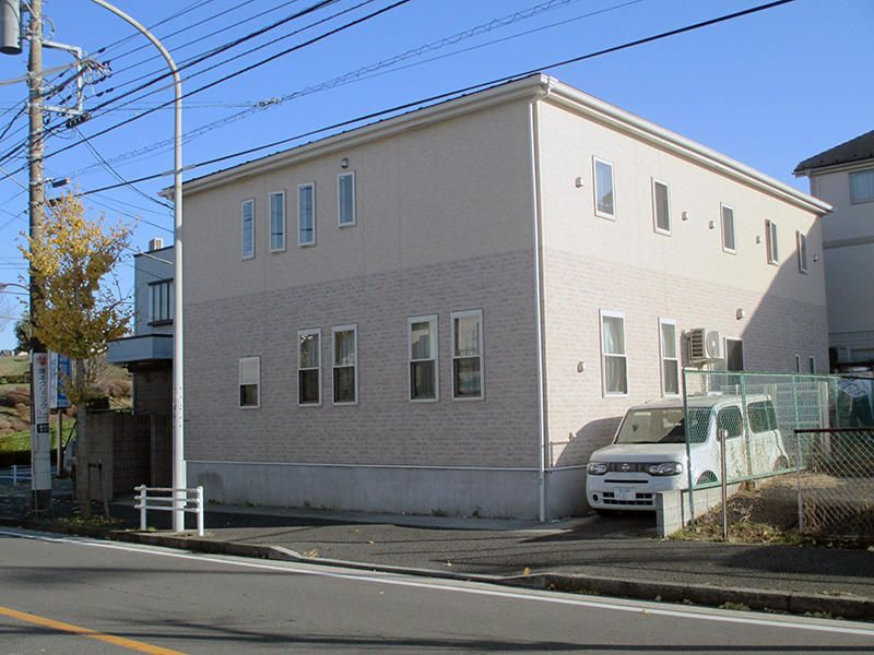 同系色のツートンカラーの外壁を持つ２階建ての施設外観