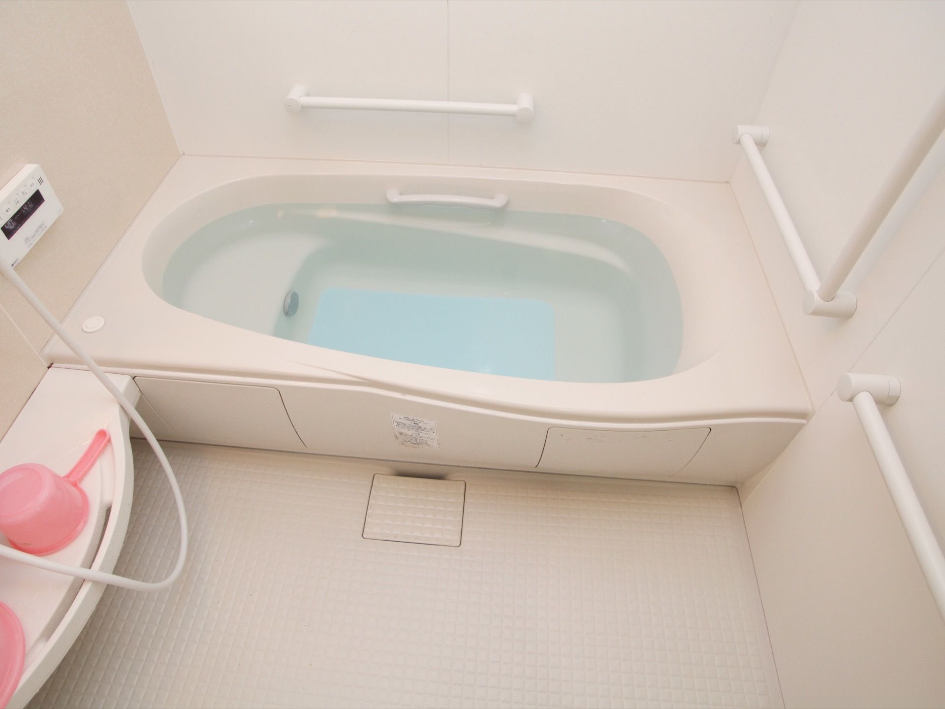 白を基調としたデザインのユニットバスである。浴槽は自動給湯機能付きであり、底には滑り止めマットが敷かれている。