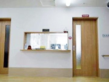 明るい雰囲気のフロントである。小物などで飾られていて、続く廊下の壁には手すりが設置されている。扉は引き戸になっている。