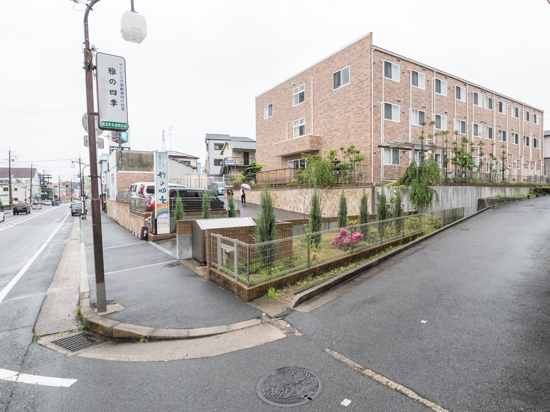 通り沿いに位置し、明るいピンクブラウン色の壁な3階建て施設建物である。入り口には大きな看板がある。玄関までは緩やかな坂である。