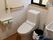 白い壁の清潔感のあるトイレである。手すりを壁に設置しており、安全に利用することができる。窓がある明るいスペースである。