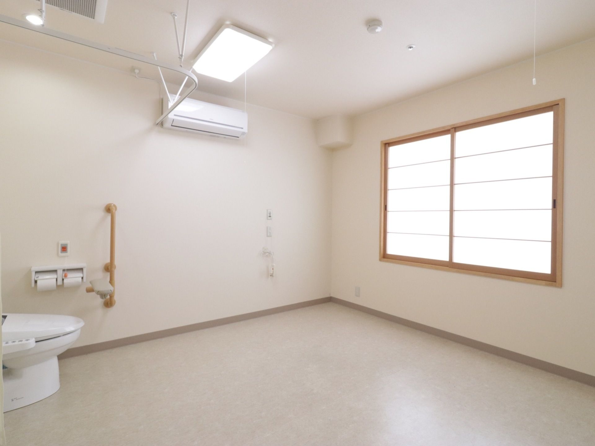 居室の入口側にトイレがあり、窓は障子が嵌められている。エアコンが完備されており、壁に２ヶ所、コンセントがある。