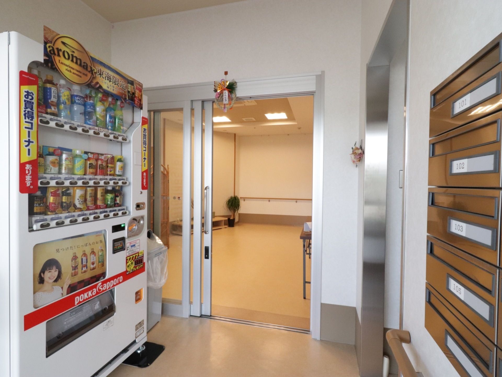 壁際に飲料水の自動販売機が設置されている。反対側には各居室の部屋番号が入った郵便受けが設けられている。