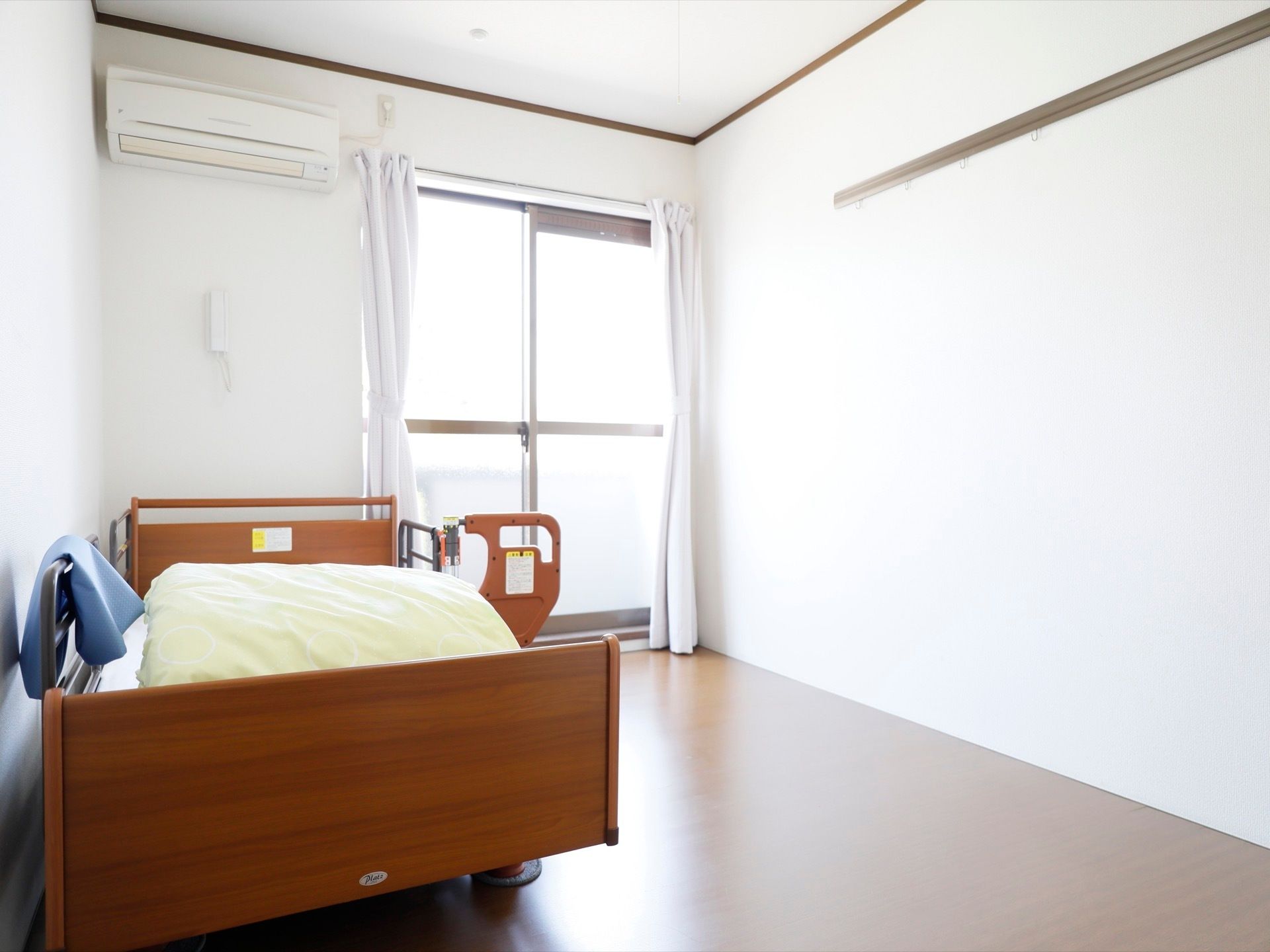 居室には窓があり、横の壁にエアコンが設置されている。介護用のベッドが完備され、サイドレールがついている。