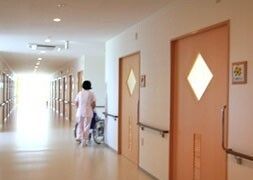 廊下を通る車椅子に乗った高齢者を介助する女性スタッフ