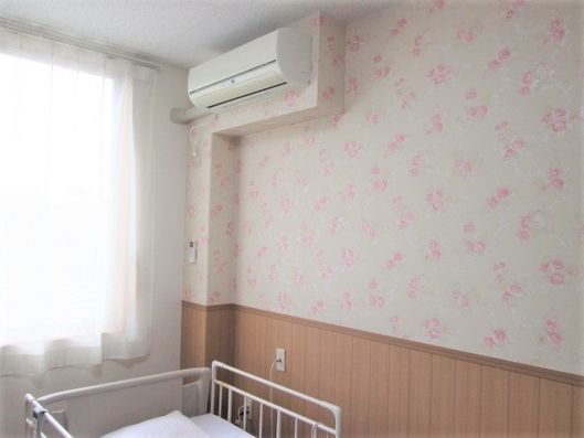 花柄の壁紙の部屋。エアコンとベッドが設置されている。