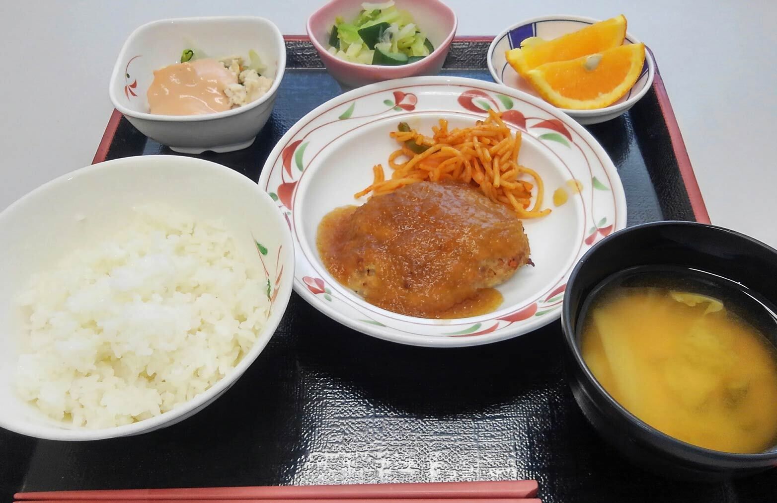 ハンバーグとスパゲッティサラダ、浅漬けとご飯と味噌汁とカットオレンジのデザート