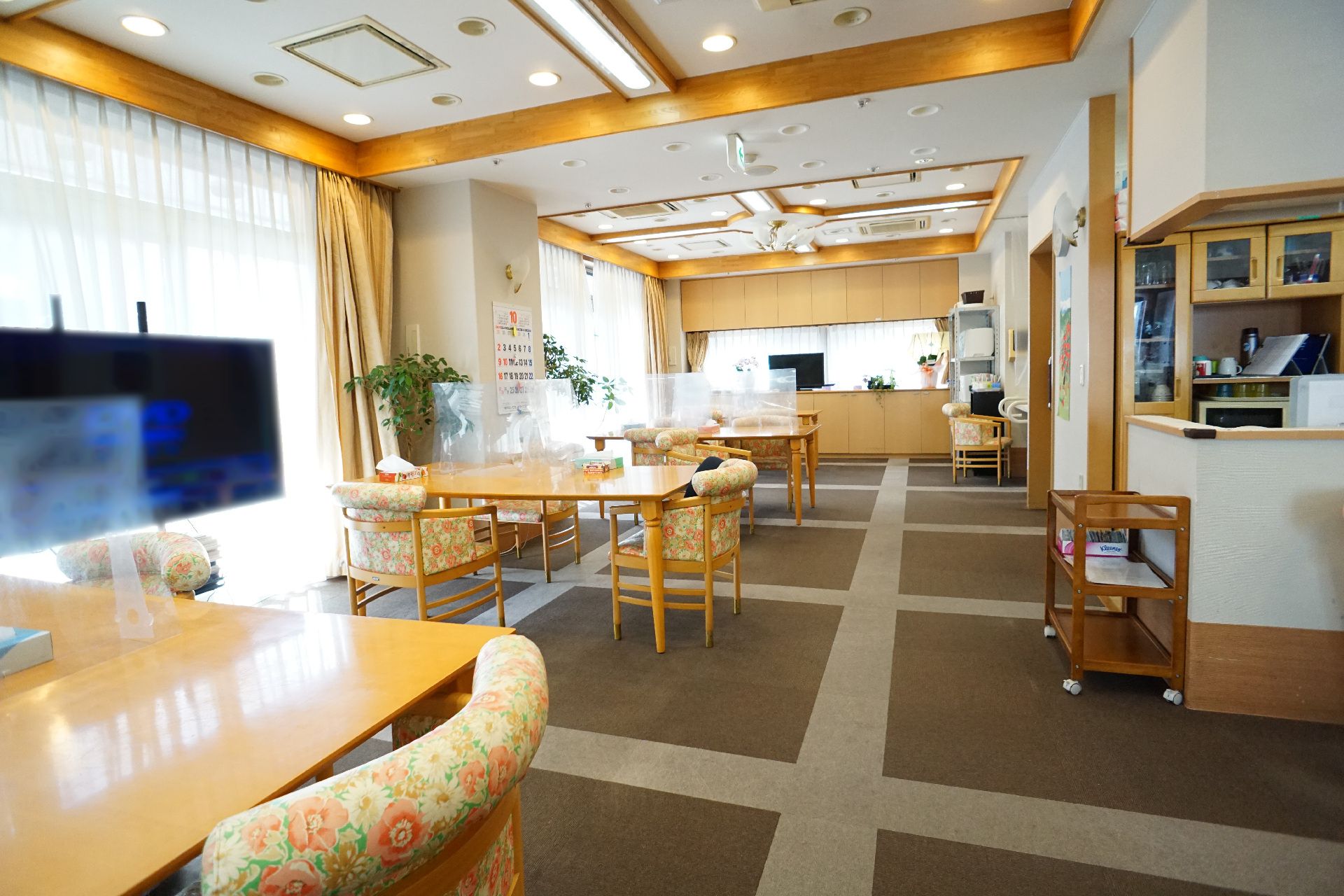 机が並んでおり仕切り板が設置されている共有スペース