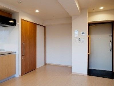 白色の引き戸タイプの扉があり、その近くの壁に黄色の手すりが設置されている居室