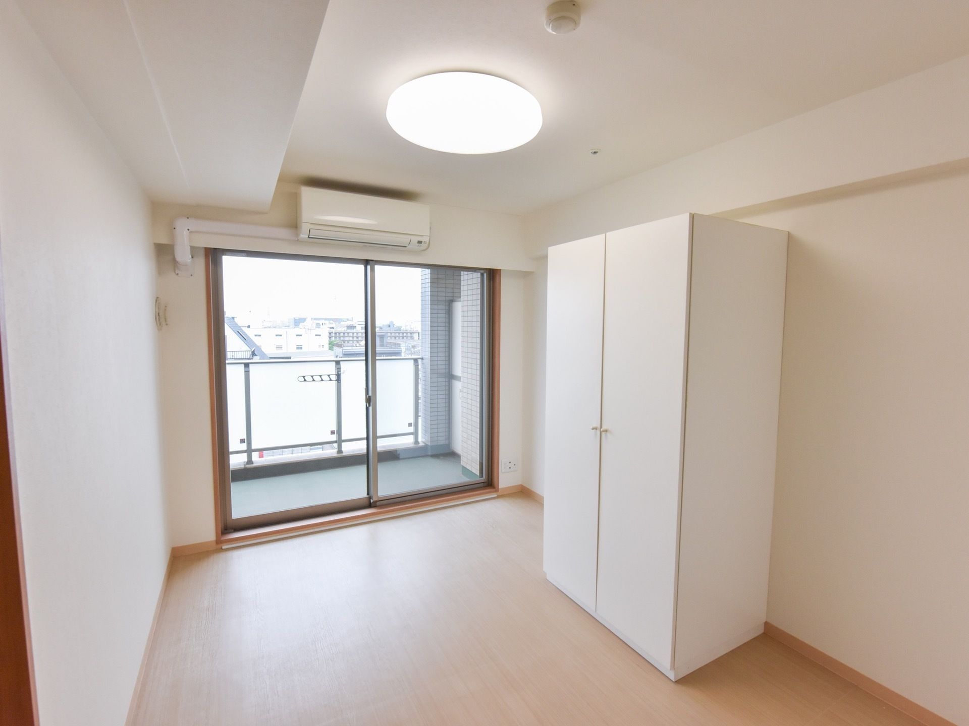 入居者様の居室は間口の大きな掃出し窓が設置され、清潔感のある空間となっている。床は淡い木肌色で木の温かみが感じられる。
