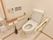 温水洗浄便座のトイレを使用している。トイレットペーパーは２ヶ所あり、壁にタッチパネルと非常ボタンが設置されている。