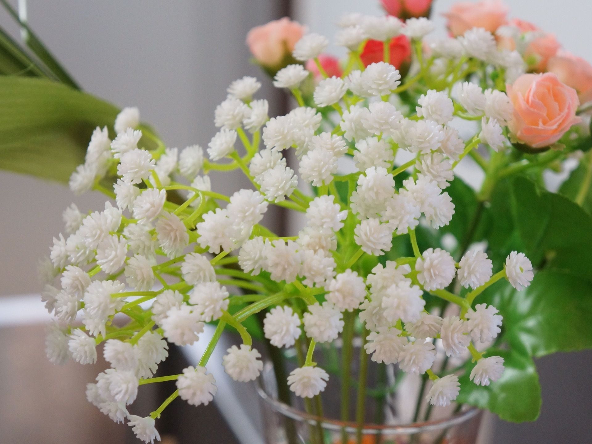 小さな白い花やピンクのバラがガラスの花瓶に生けられており、共有スペースのカウンターの上に置かれている。