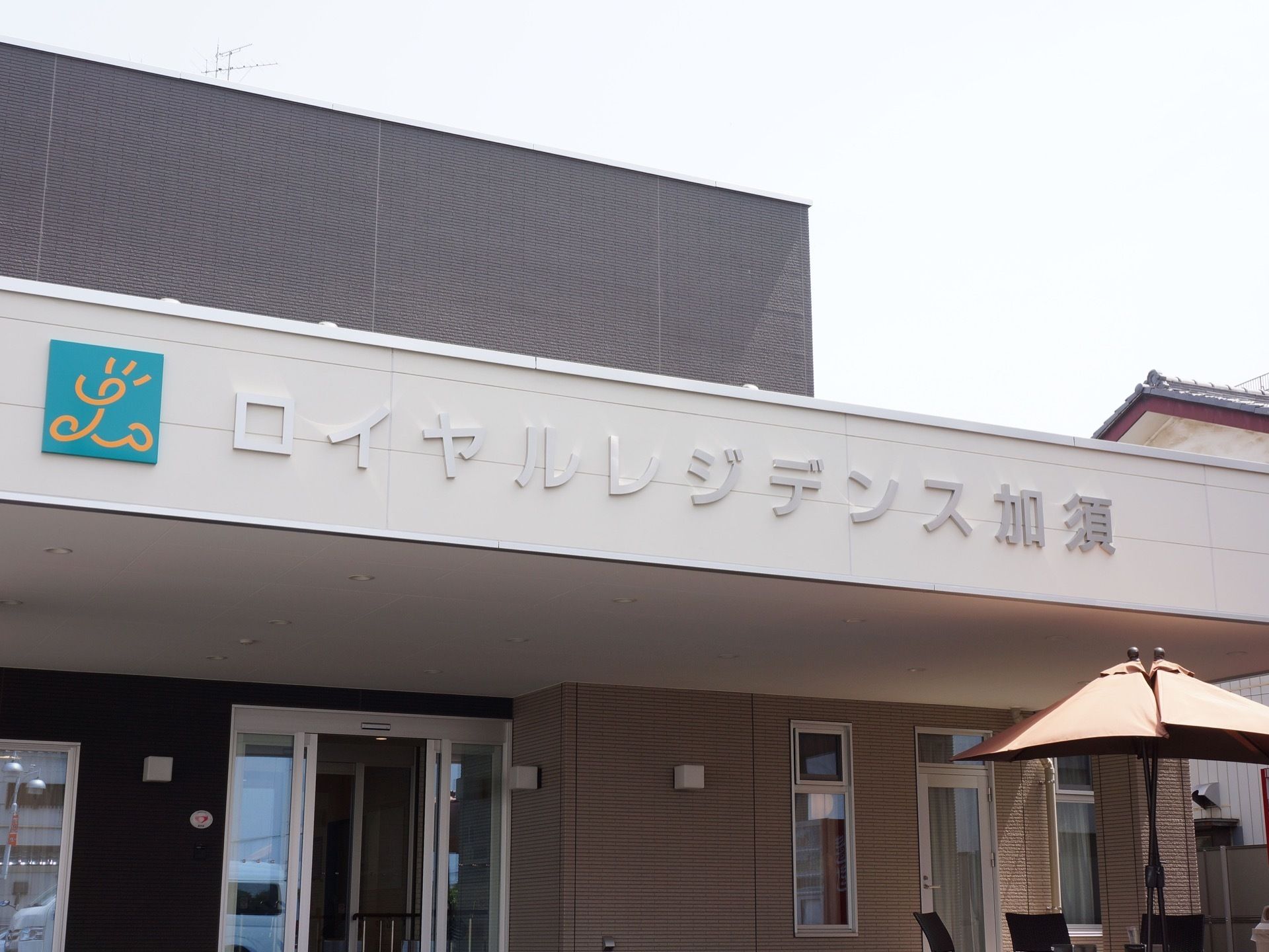 施設玄関入口の前には大きな屋根がある。屋根には施設のロゴ、ロゴの横には施設名が大きく書かれている。どちらも立体的になっている。