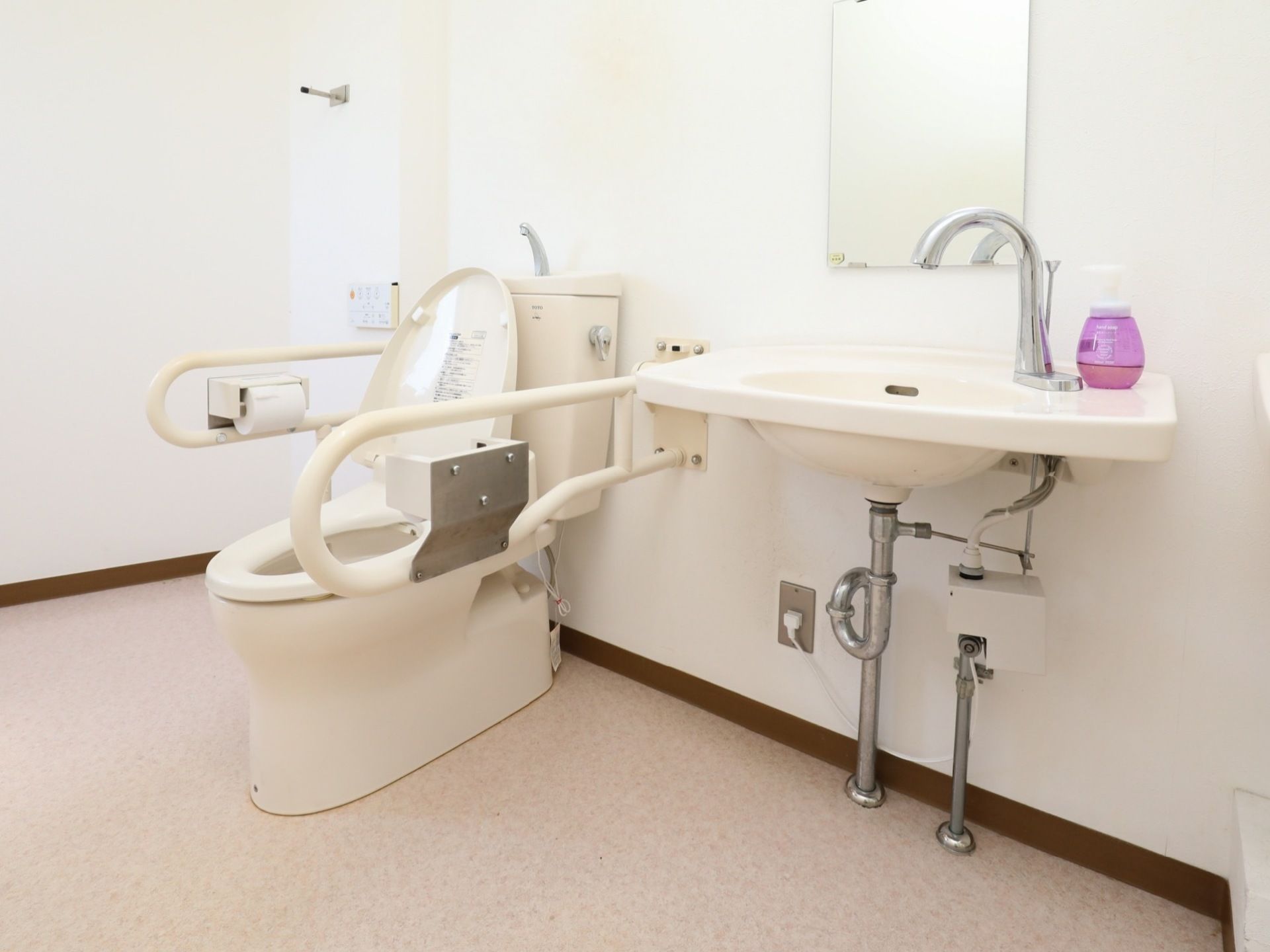 広々としたスペースにトイレと手洗い器が設置されている。手洗い器は自動水栓となっているので快適に利用できる。