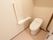 清潔感のある広々とした温水洗浄便座のトイレである。利用しやすいように手すりを設置している。緊急呼び出しボタンも備わっている。
