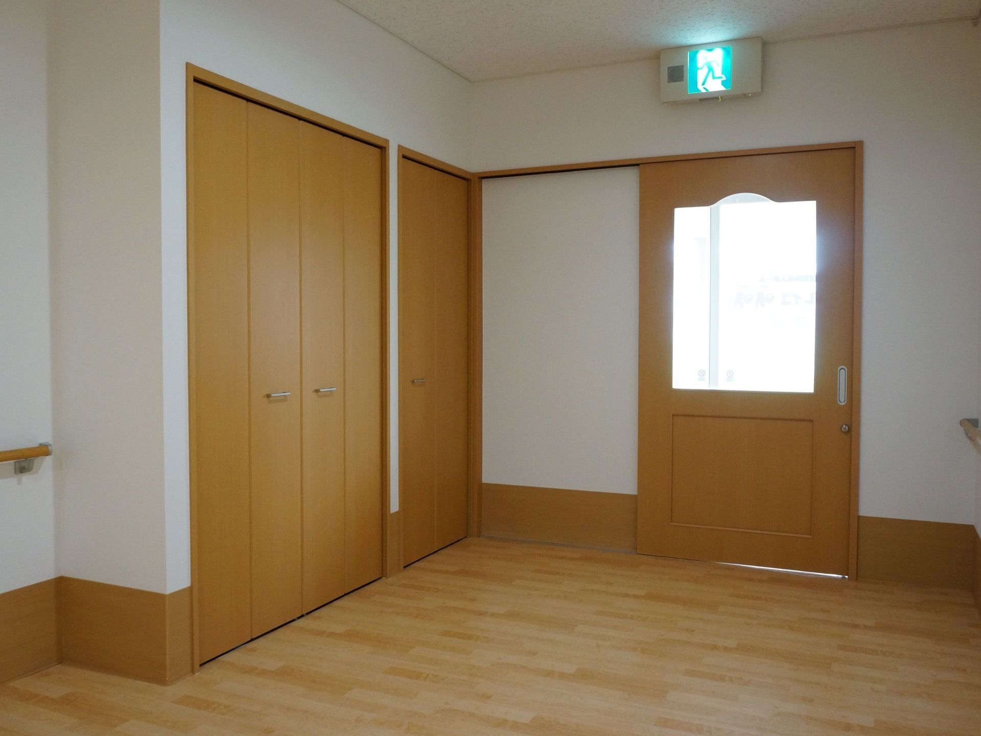 内装は白色のクロスの壁に木目のフローリングの床である。スライドドアの入り口の頭上に非常口誘導灯が設置されている。