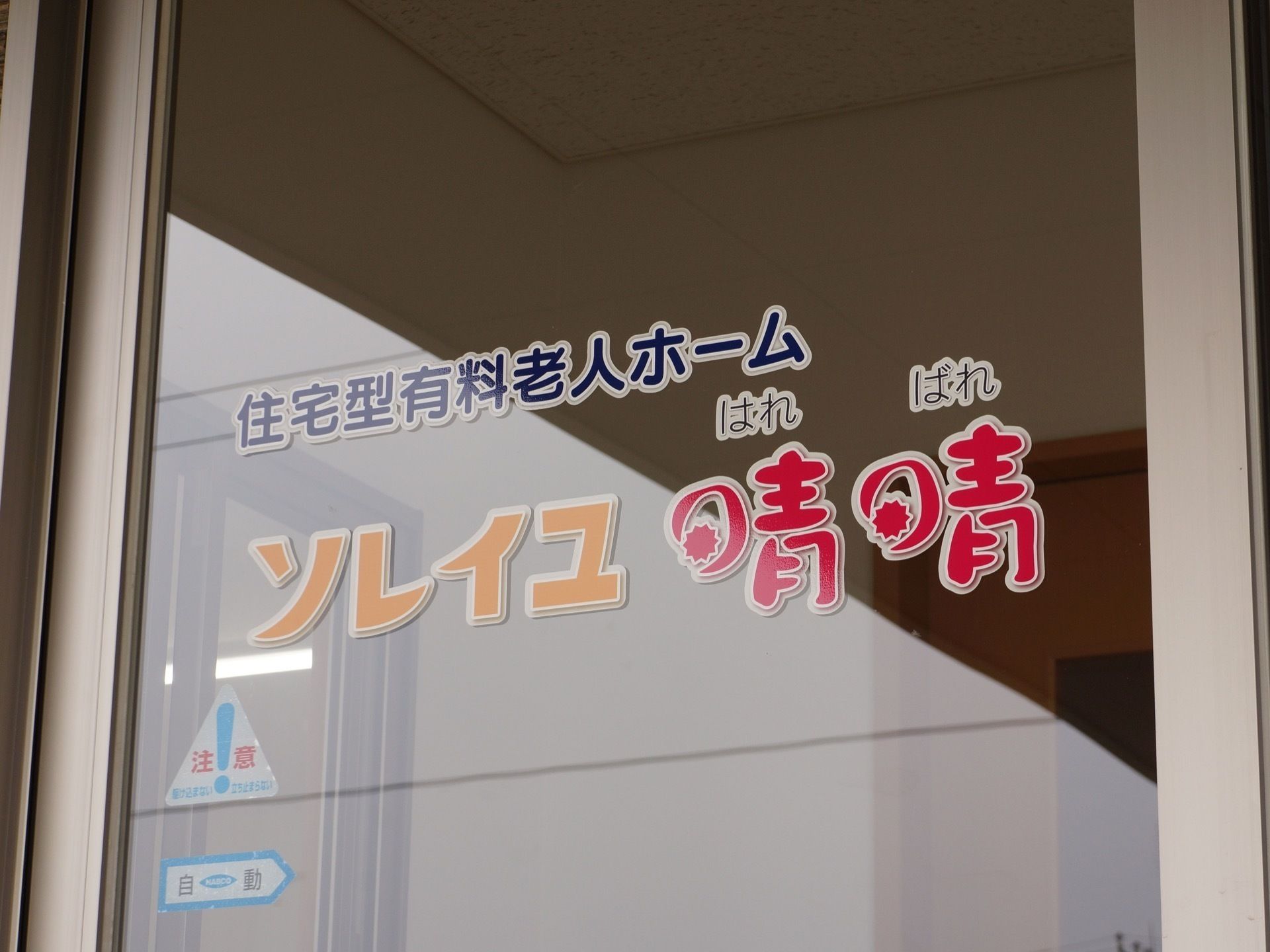 提供サービスの下に施設名称が書かれている自動扉の玄関