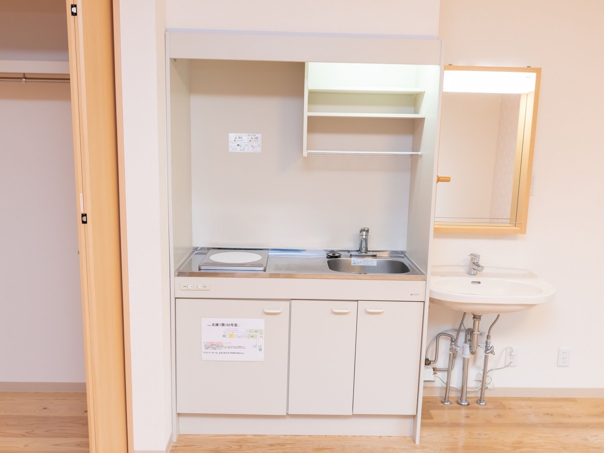 部屋にはミニキッチンが用意されている。大きめのクローゼットが設置されている。洗面スペースが併設されており鏡が備えつけられている。