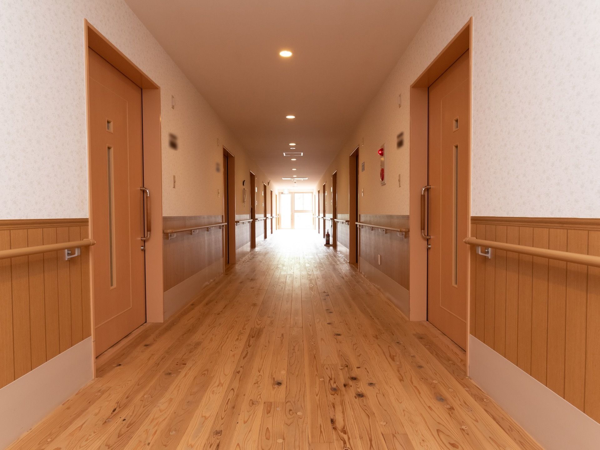木の温もりを感じる廊下である。壁には手すりが備えつけられている。各部屋の扉はベージュで、スライド式になっている。