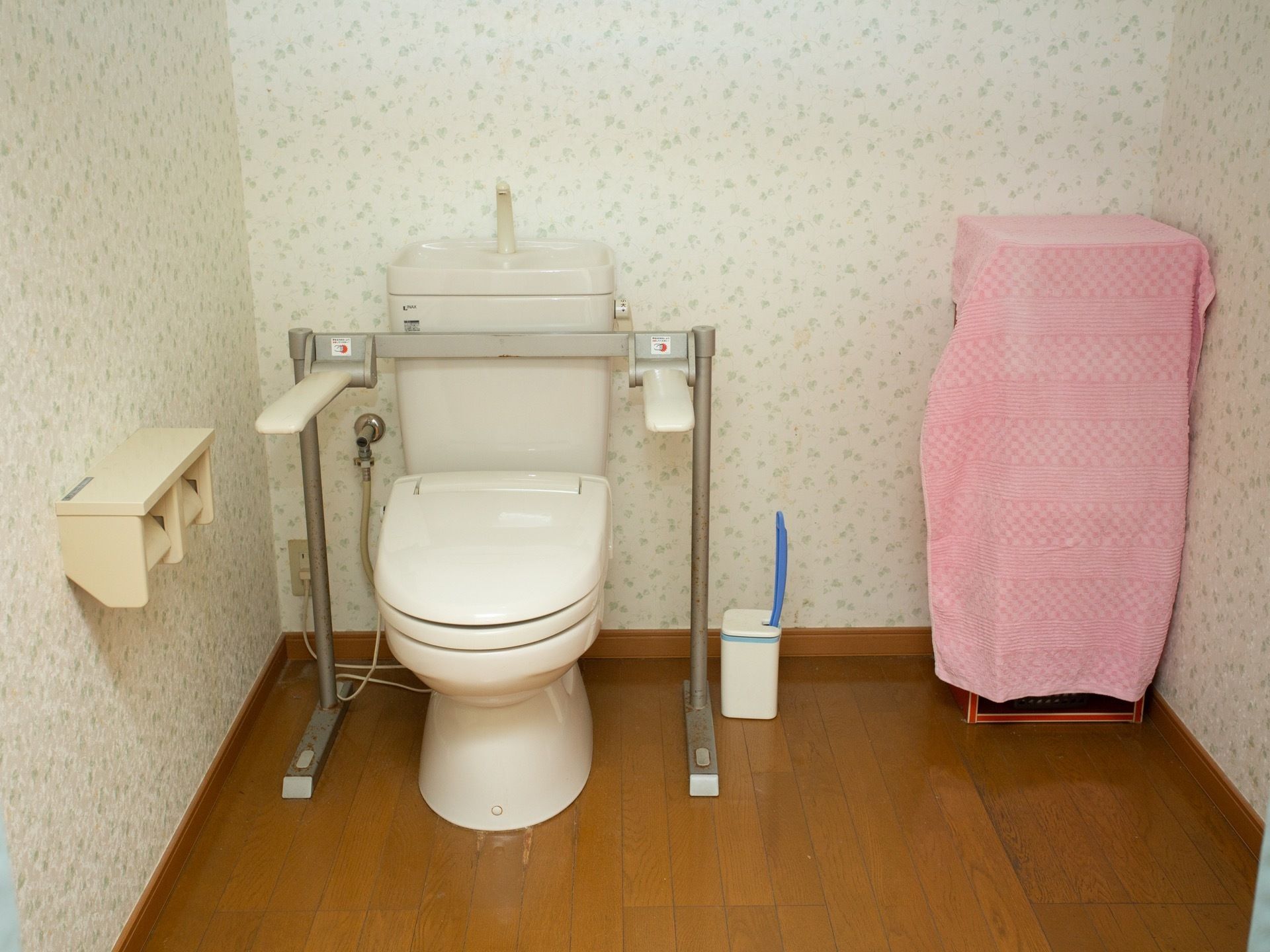 トイレには温水洗浄式の便座がある。また便座の脇に、立つ時や座る時に身体が支えられる白いバーが付いている。