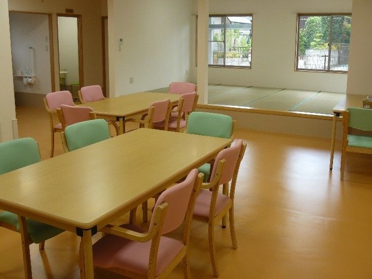 通路が広くとられた食堂。テーブルを囲むように４・５脚の椅子が置かれている。奥には畳敷きのスペースがある。