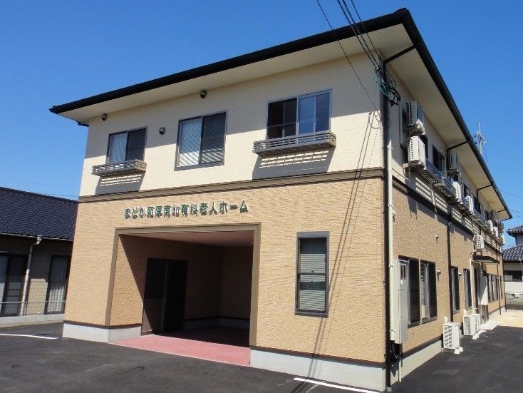 小規模ホームならではの2階建てのアパートのような外観。ベージュ系のツートーンカラーの外壁に居室の窓が並ぶ。