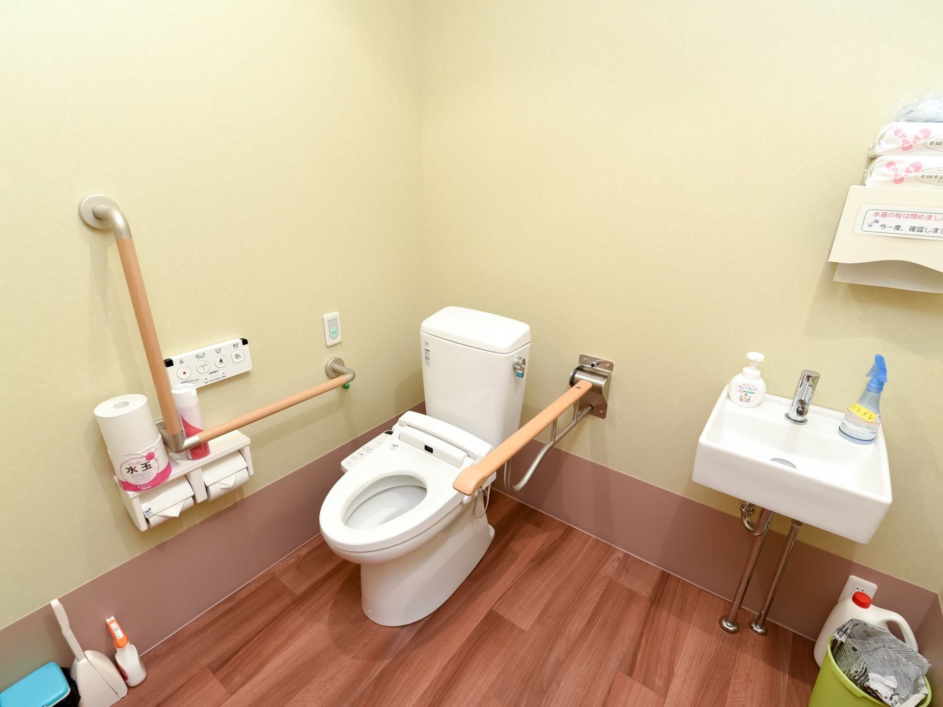 洗面台が備わった広々としたトイレである。便器横の壁には、可動式とＬ型手すり、ナースコールが設置されている。