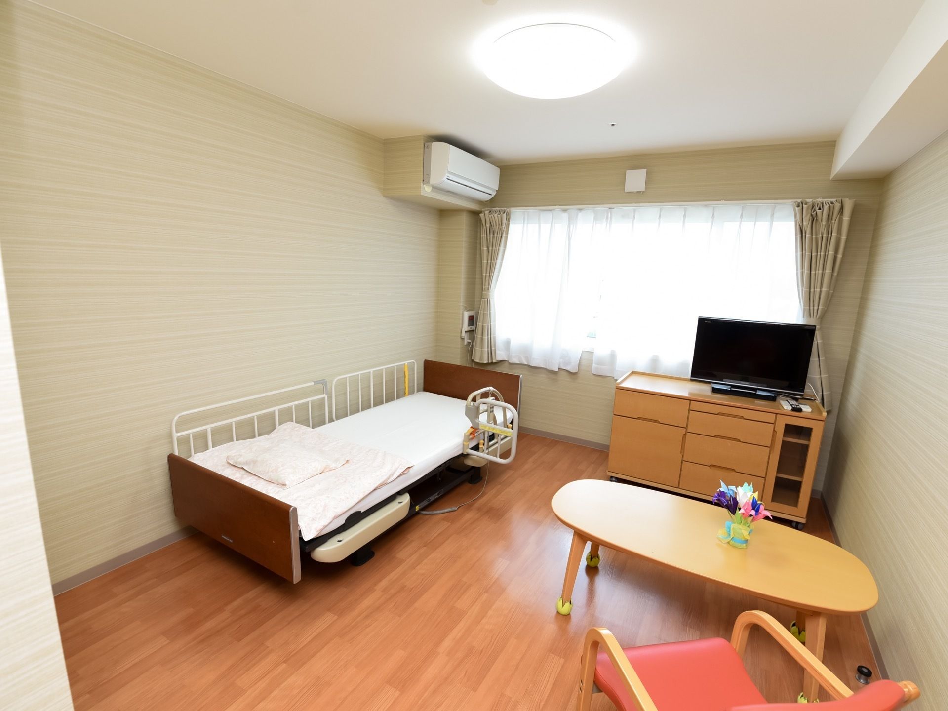居室の窓は大きく開放的な雰囲気である。床と家具は木目調で、シンプルかつ親しみやすい空間になっている。
