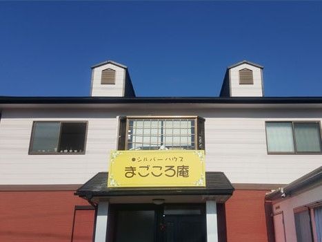 屋根に突出部分があり、えんじ色と白色のバイカラーの壁色の施設外観