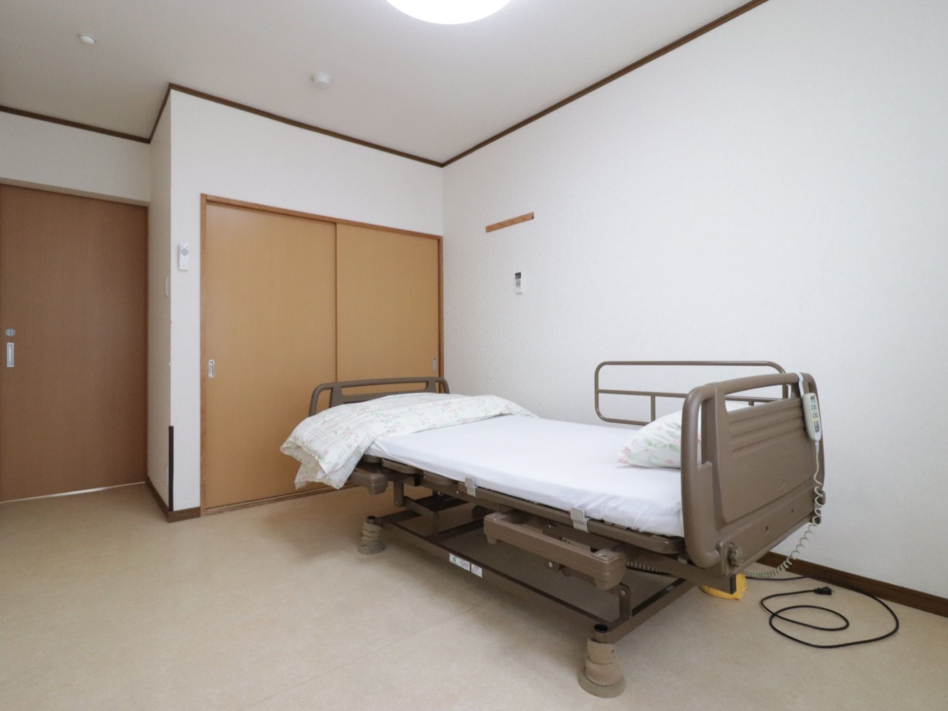 居室内では、可動式のベッドを設置して、起床を助けることも可能である。扉は、木目調の開き戸で、押入れ収納も可能である。