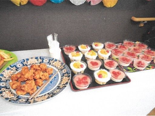 入居者様同士が取り分けて食事を楽しむ機会を設けている。大皿にから揚げと取り分けるお箸が用意されている。食後のデザートもある。