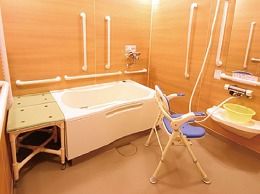 手すりやシャワーチェアが設置され安全面に配慮されている。一般家庭のような雰囲気も保たれた浴室である。