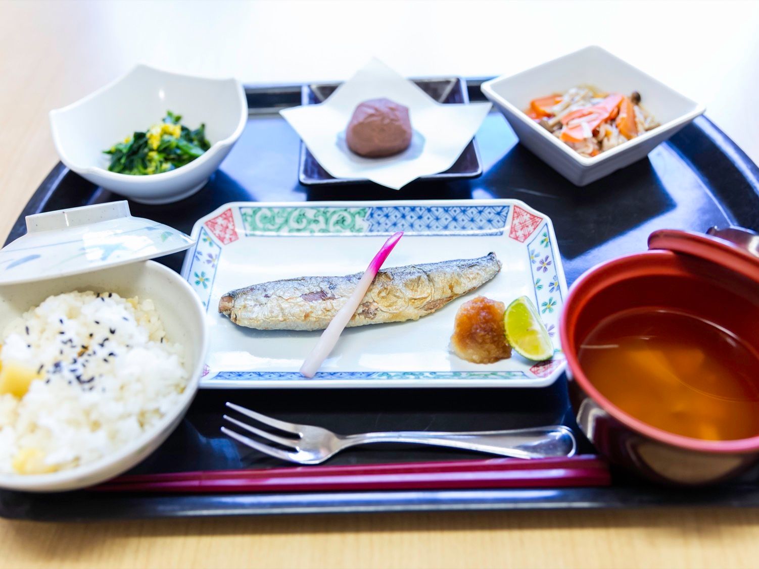 黒い和風のお盆に、料理がきれいにならべられている。本日の食事は魚をメインとした和食である。小鉢もある。
