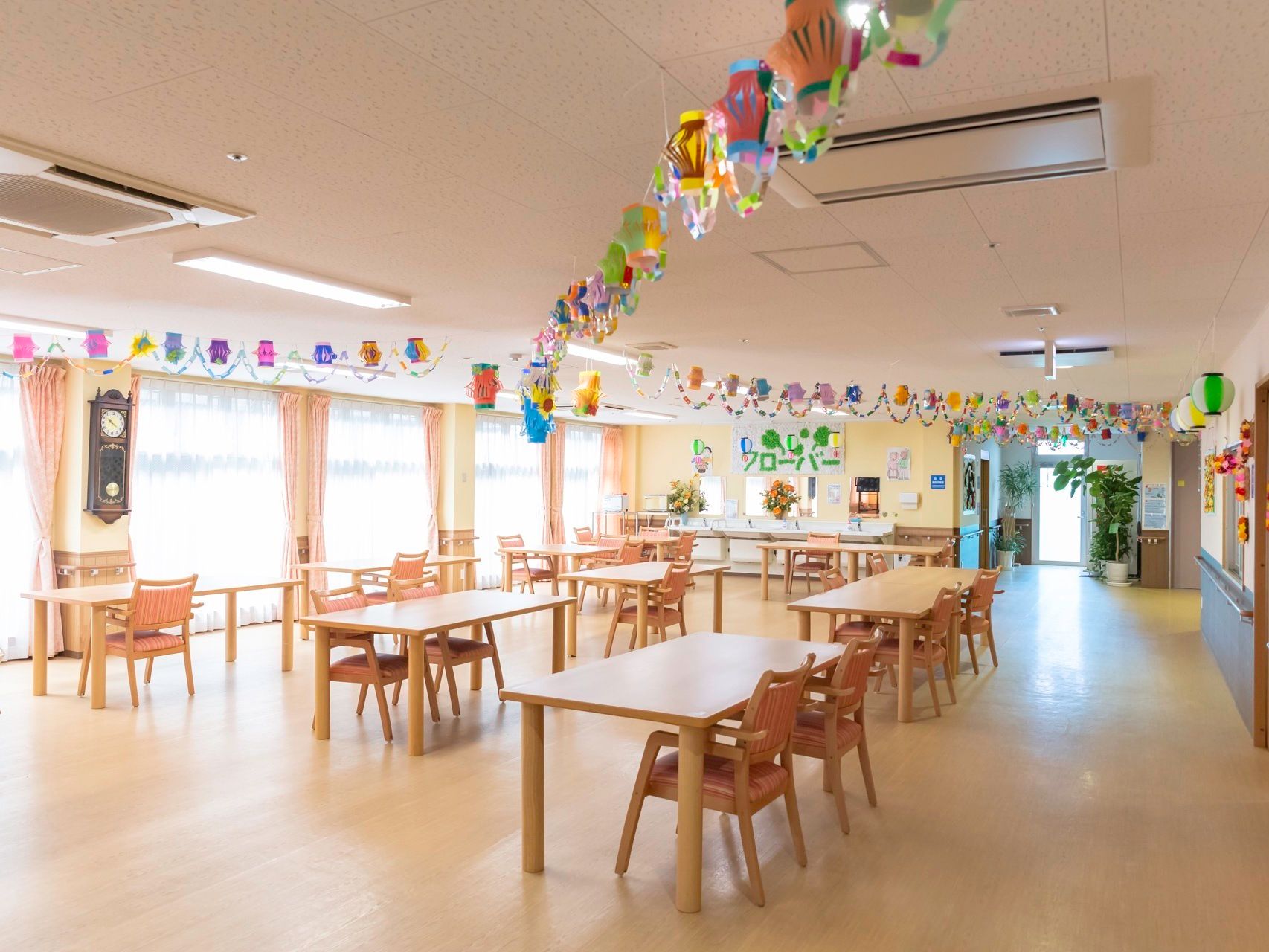 明るい色のテーブルセットが複数配置された、開放感たっぷりの食堂である。壁側には手すりが設けられている。